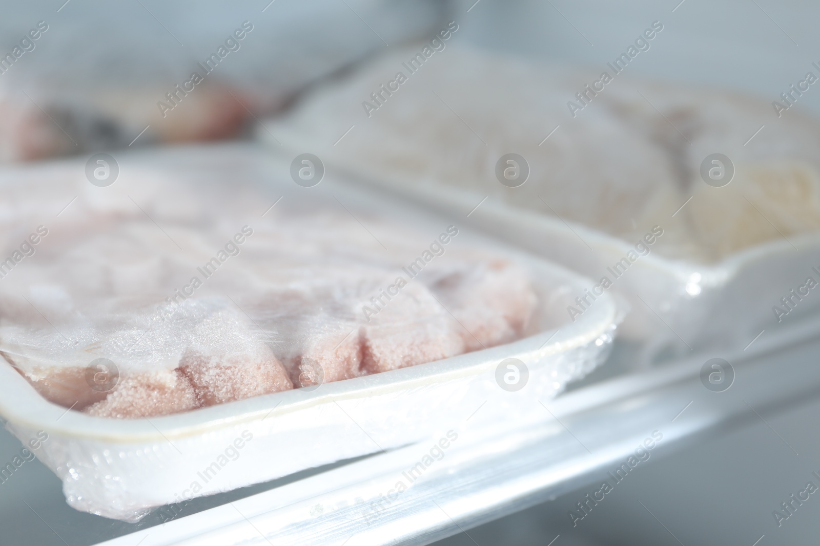 Photo of Different frozen meat products on refrigerator shelf, closeup