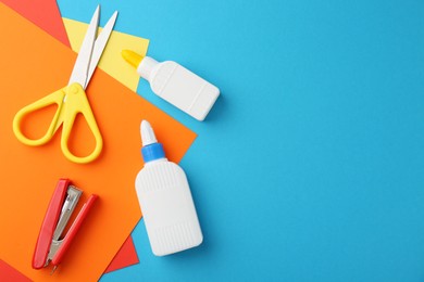 Photo of Glue, colorful paper, stapler and scissors on light blue background, flat lay. Space for text