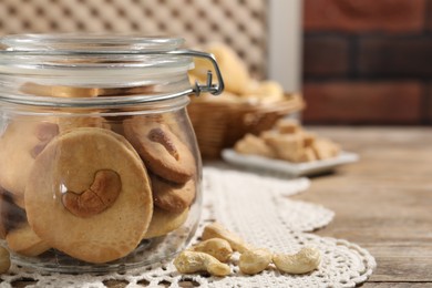 Photo of Tasty cashew cookies in jar on wooden table, closeup. Space for text