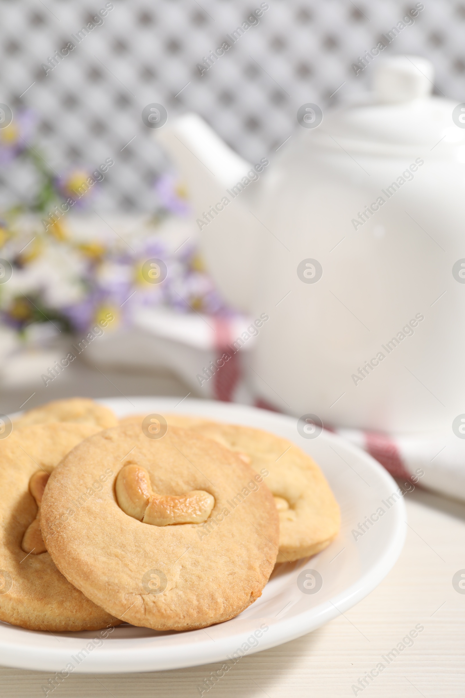 Photo of Plate with tasty cashew cookies on white wooden table, closeup. Space for text