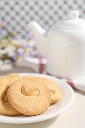 Photo of Plate with tasty cashew cookies on white wooden table, closeup. Space for text