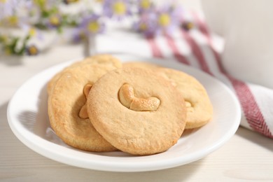 Photo of Plate with tasty cashew cookies on white wooden table, closeup