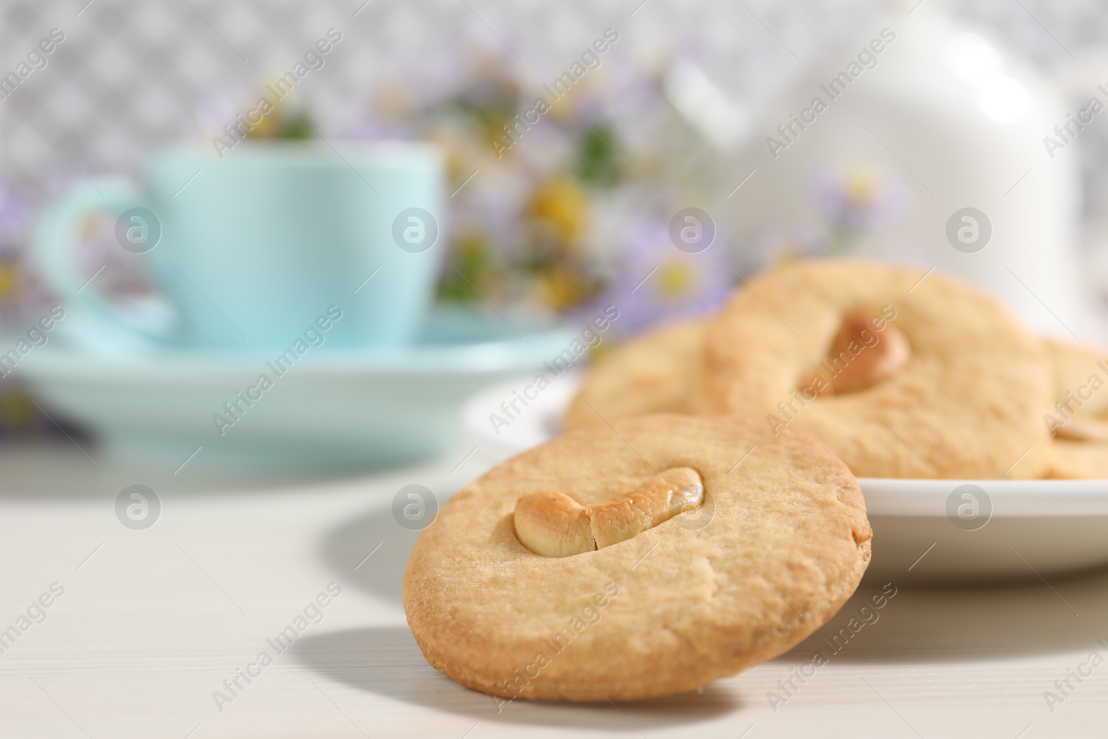 Photo of Plate with tasty cashew cookies on white wooden table, closeup. Space for text