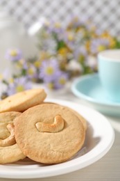 Photo of Plate with tasty cashew cookies on white wooden table, closeup. Space for text