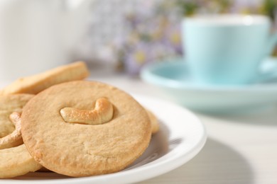 Photo of Plate with tasty cashew cookies on white wooden table, closeup. Space for text