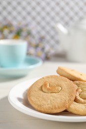 Photo of Plate with tasty cashew cookies on white wooden table, closeup. Space for text