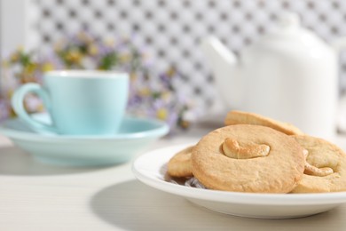 Photo of Plate with tasty cashew cookies on white wooden table, closeup. Space for text