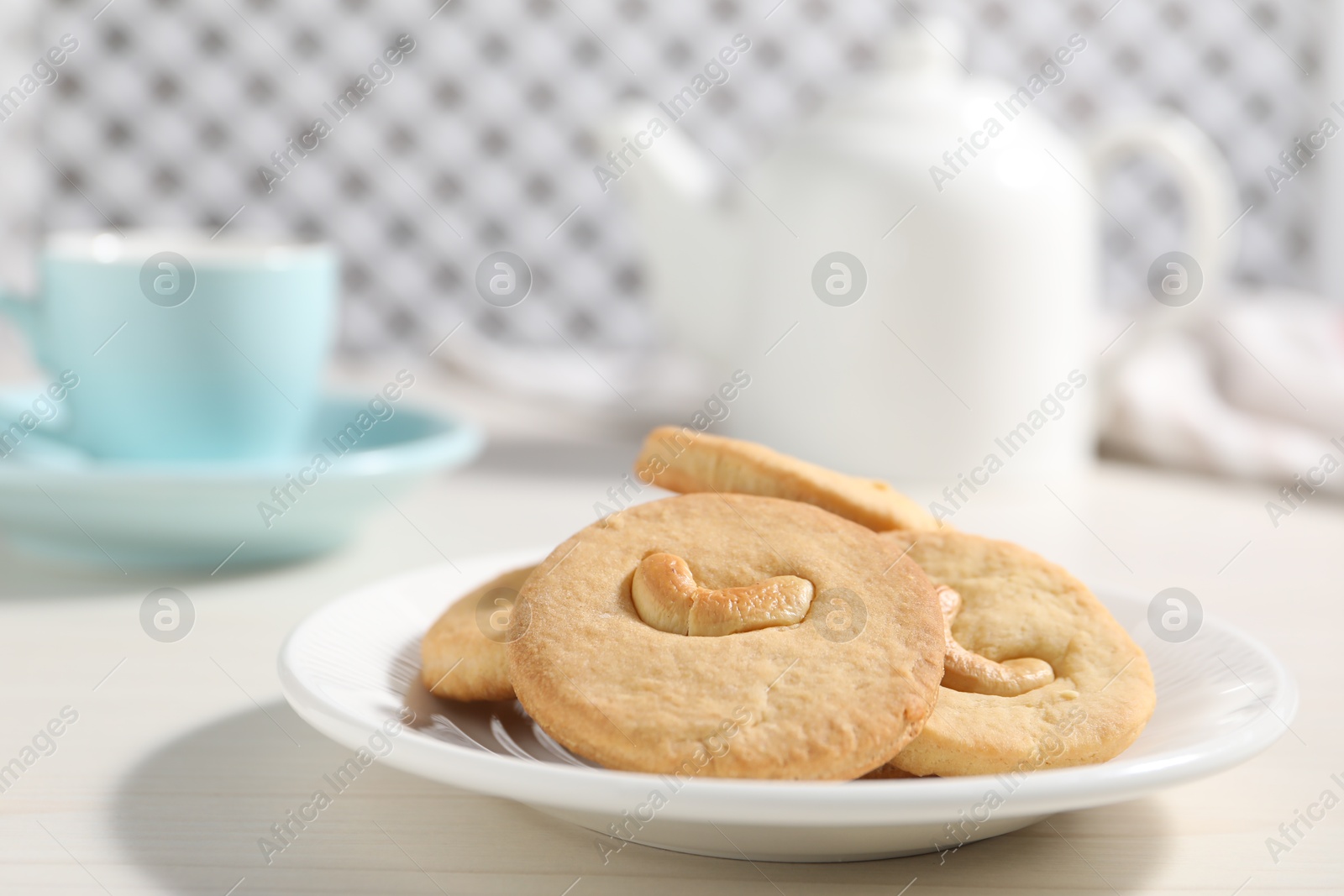 Photo of Plate with tasty cashew cookies on white wooden table, closeup. Space for text