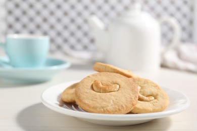 Photo of Plate with tasty cashew cookies on white wooden table, closeup. Space for text