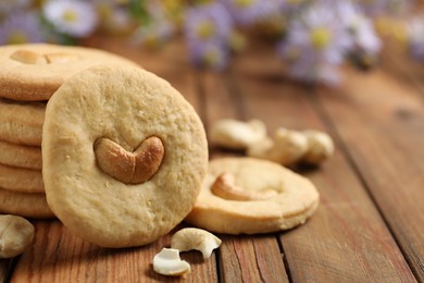 Photo of Tasty cashew cookies on wooden table, closeup. Space for text