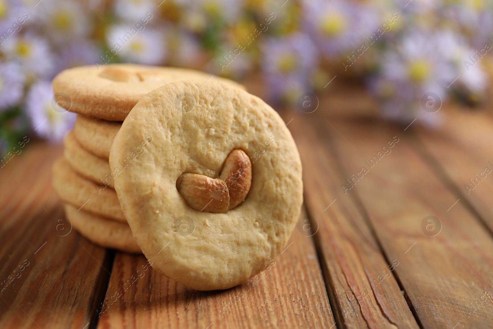 Photo of Tasty cashew cookies on wooden table, closeup. Space for text