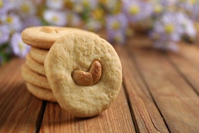 Photo of Tasty cashew cookies on wooden table, closeup. Space for text