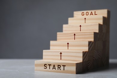 Image of Stair of wooden blocks with words Start and Goal on at beginning and at end. Steps to success concept