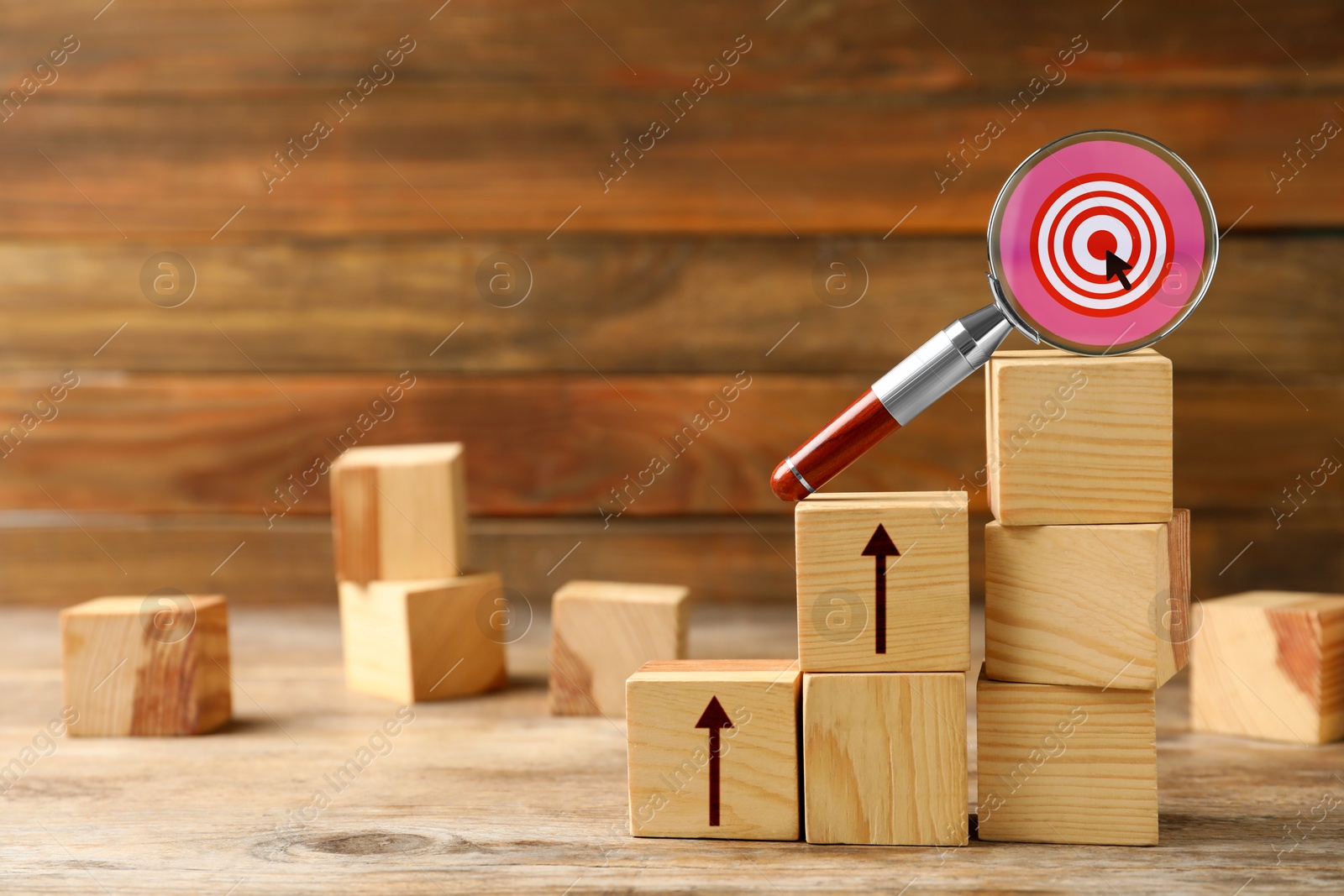 Image of Stair made wooden cubes with arrows and magnifying glass with target on top. Steps to success concept