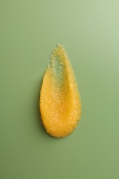 Photo of Smear of body scrub on green background, top view