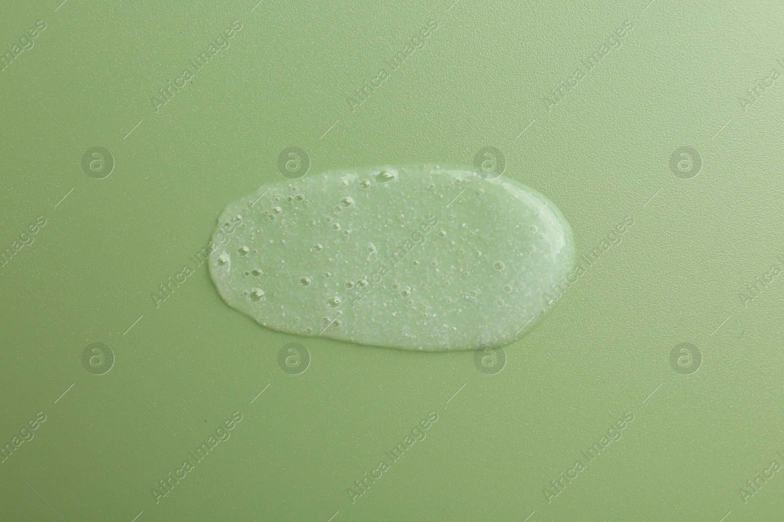 Photo of Smear of body scrub on green background, top view