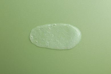 Photo of Smear of body scrub on green background, top view