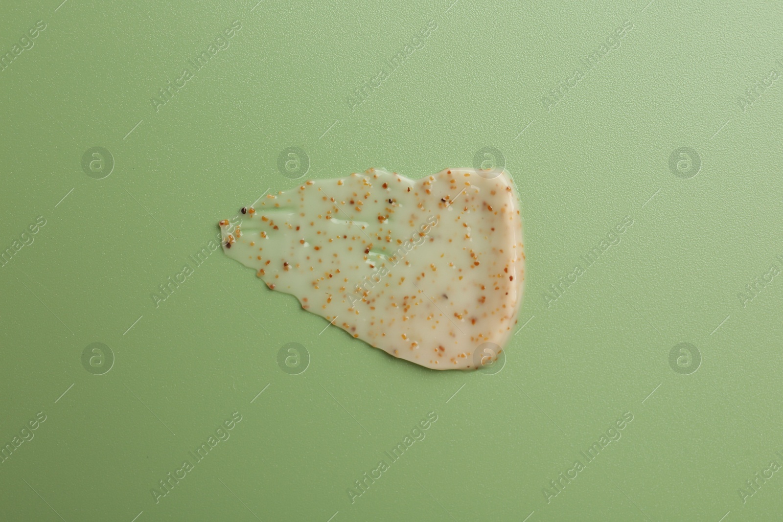 Photo of Smear of body scrub on green background, top view