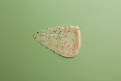 Photo of Smear of body scrub on green background, top view