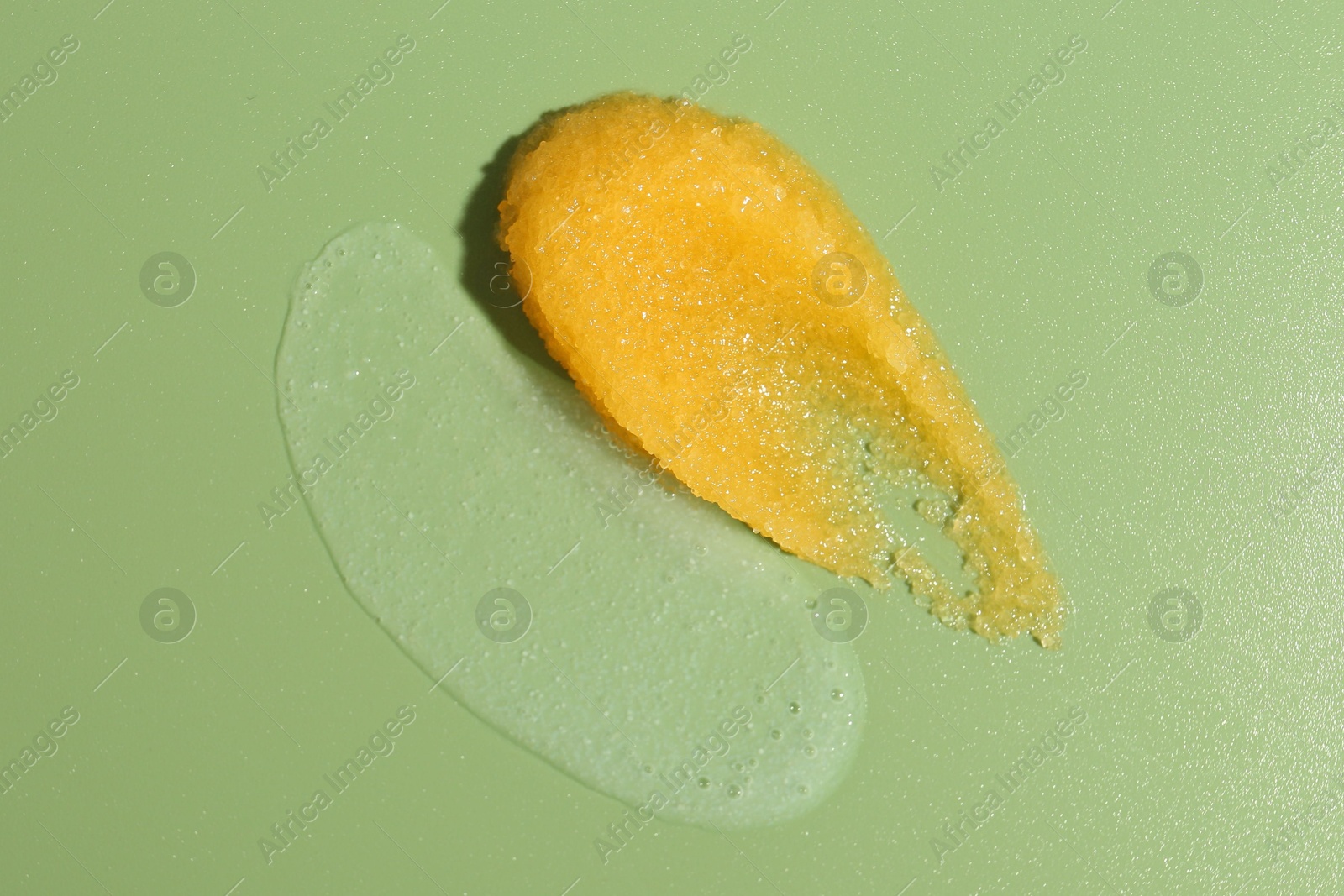 Photo of Smears of body scrubs on green background, top view