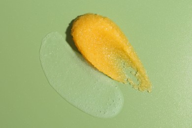 Photo of Smears of body scrubs on green background, top view