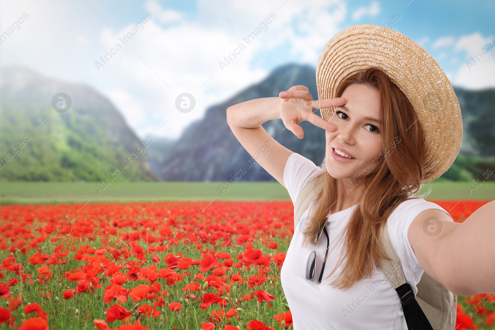 Image of Beautiful woman in straw hat taking selfie in flower meadow