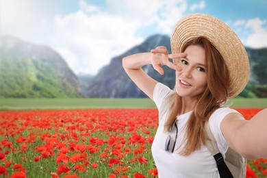 Beautiful woman in straw hat taking selfie in flower meadow