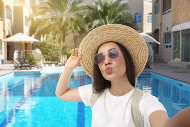 Beautiful woman in straw hat taking selfie at sea resort