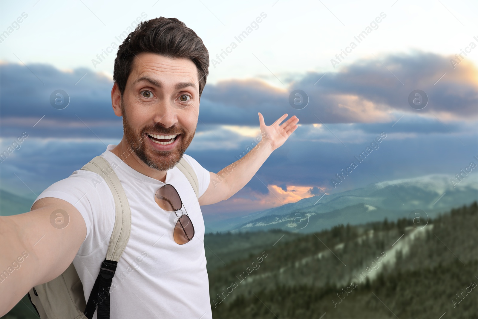 Image of Happy man with backpack taking selfie in mountains