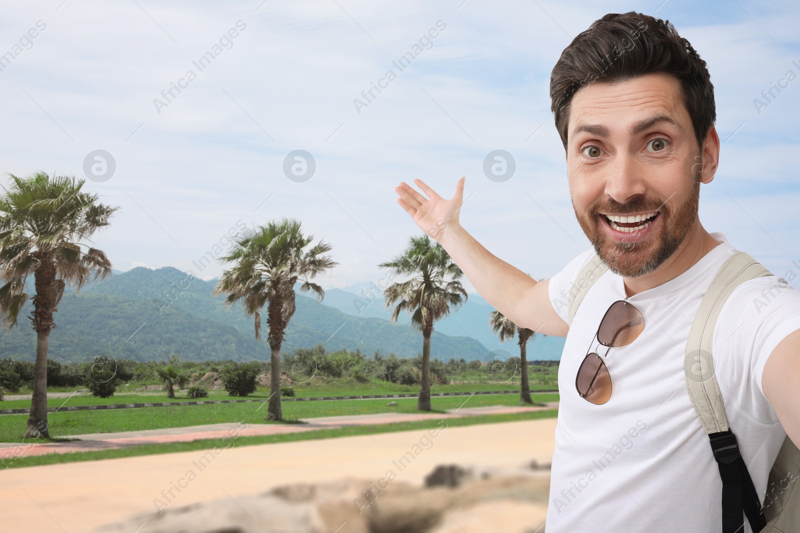 Image of Happy man with backpack taking selfie in nature