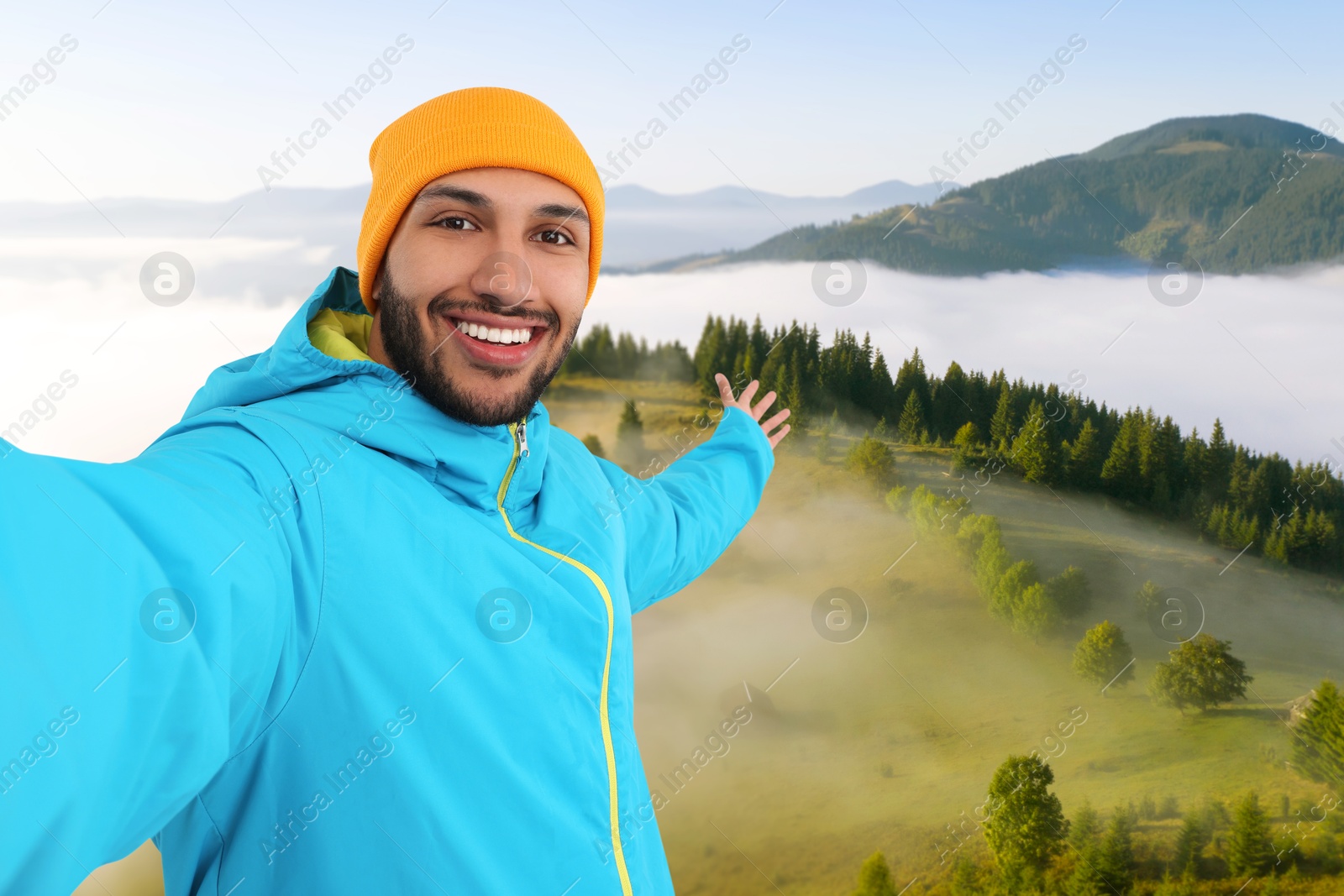 Image of Happy man in hat taking selfie in mountains