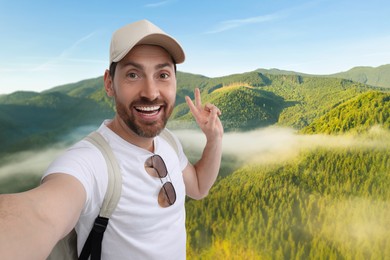 Happy man in cap taking selfie in mountains