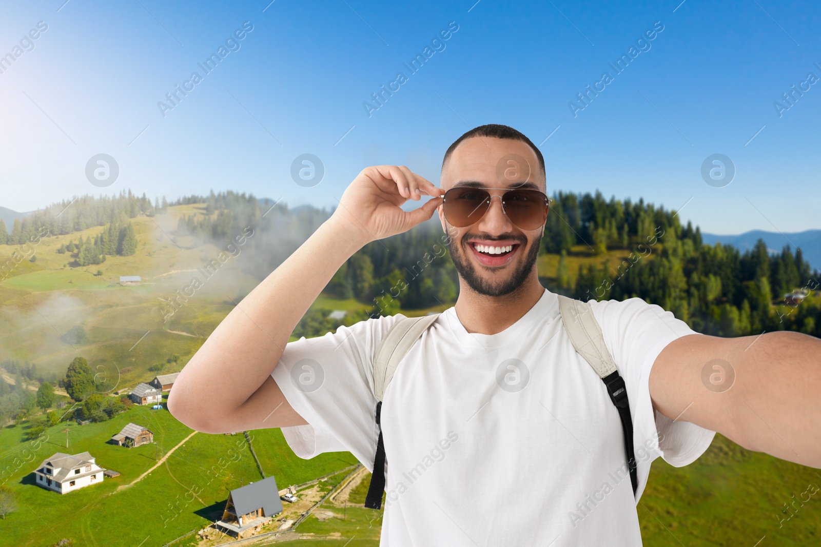 Image of Happy man with sunglasses taking selfie in mountains