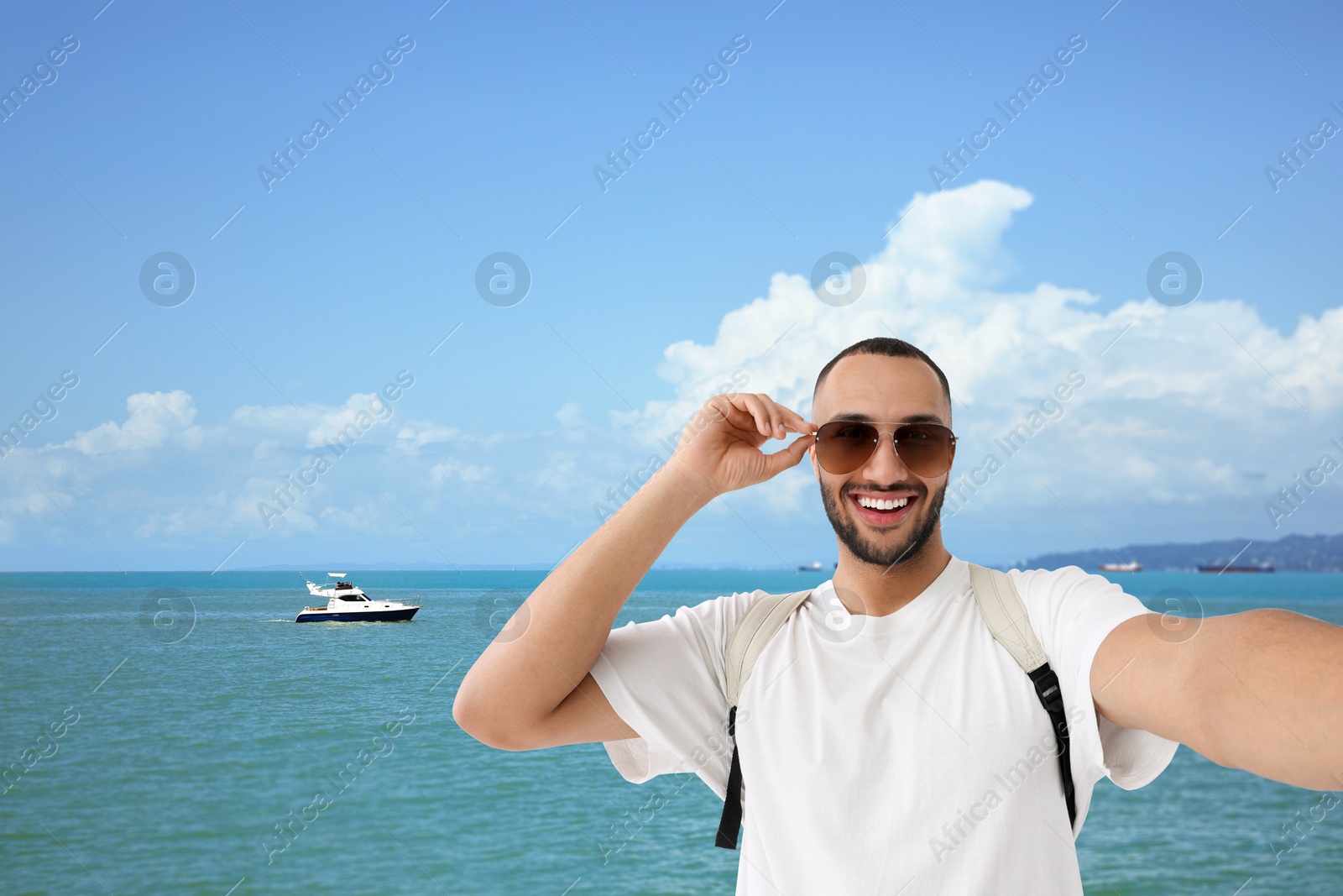 Image of Happy man with sunglasses taking selfie near sea