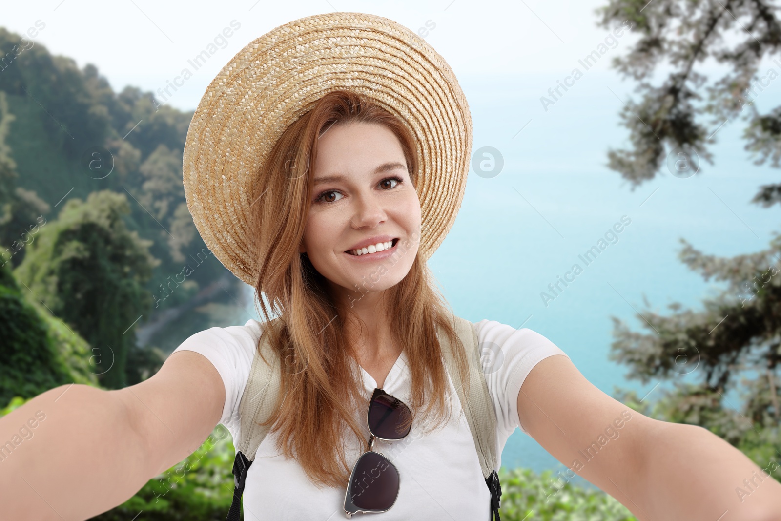 Image of Happy woman in straw hat taking selfie near sea