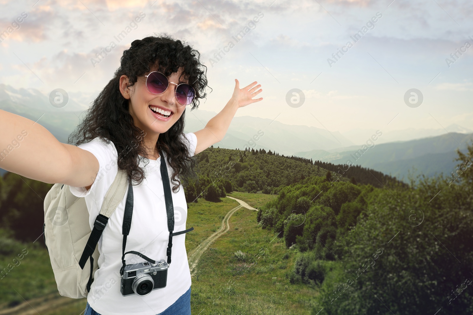 Image of Beautiful woman with sunglasses and camera taking selfie in mountains