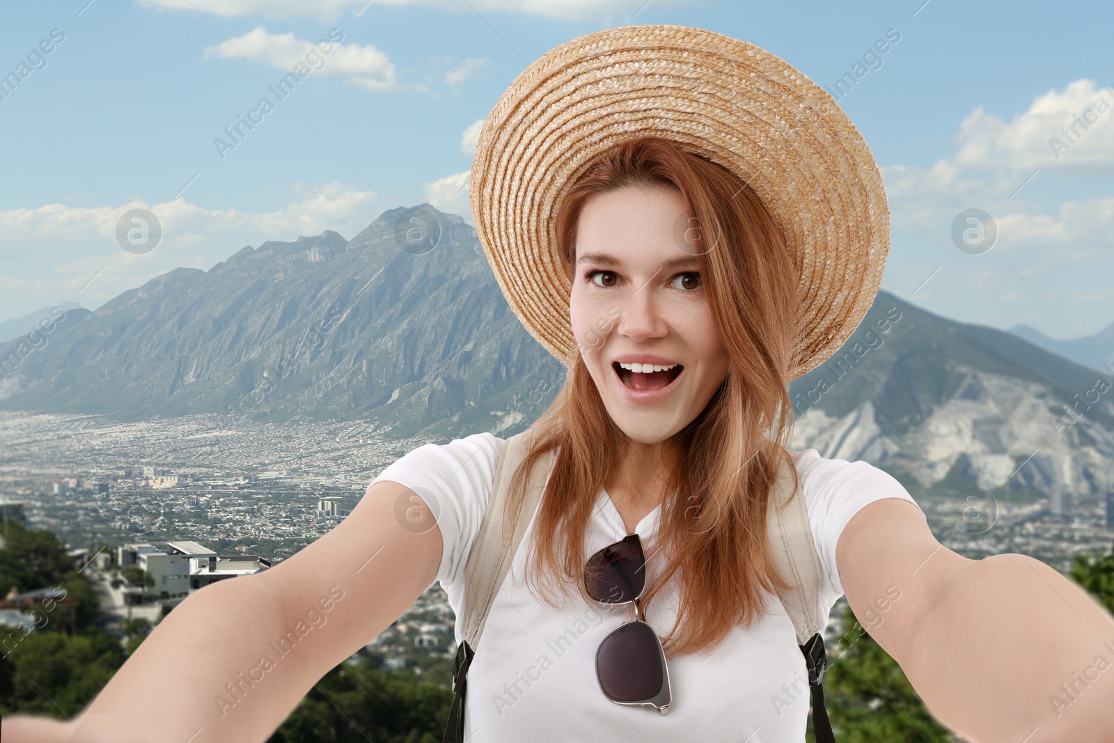 Image of Happy woman in straw hat taking selfie in mountains