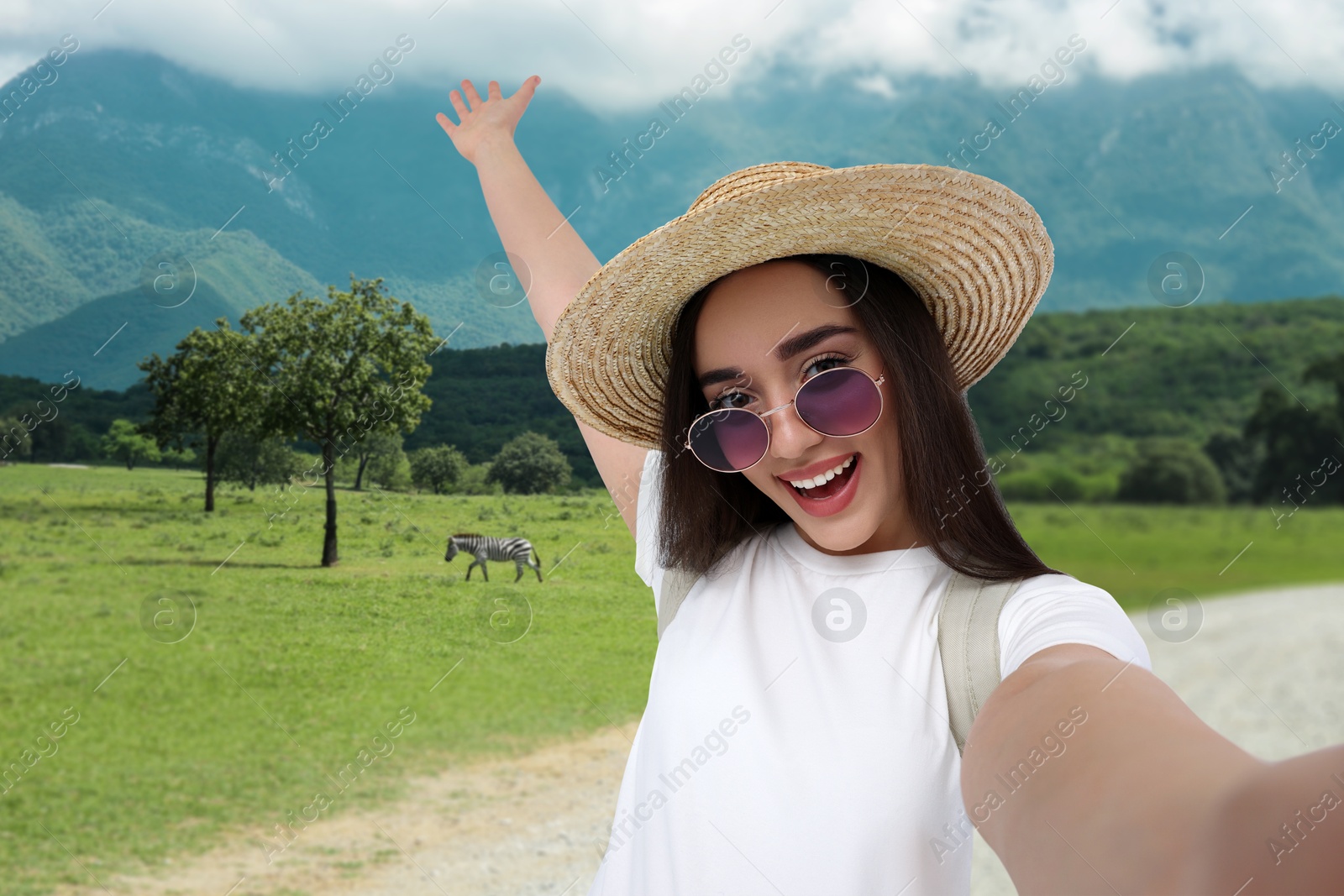 Image of Happy woman in straw hat taking selfie in nature