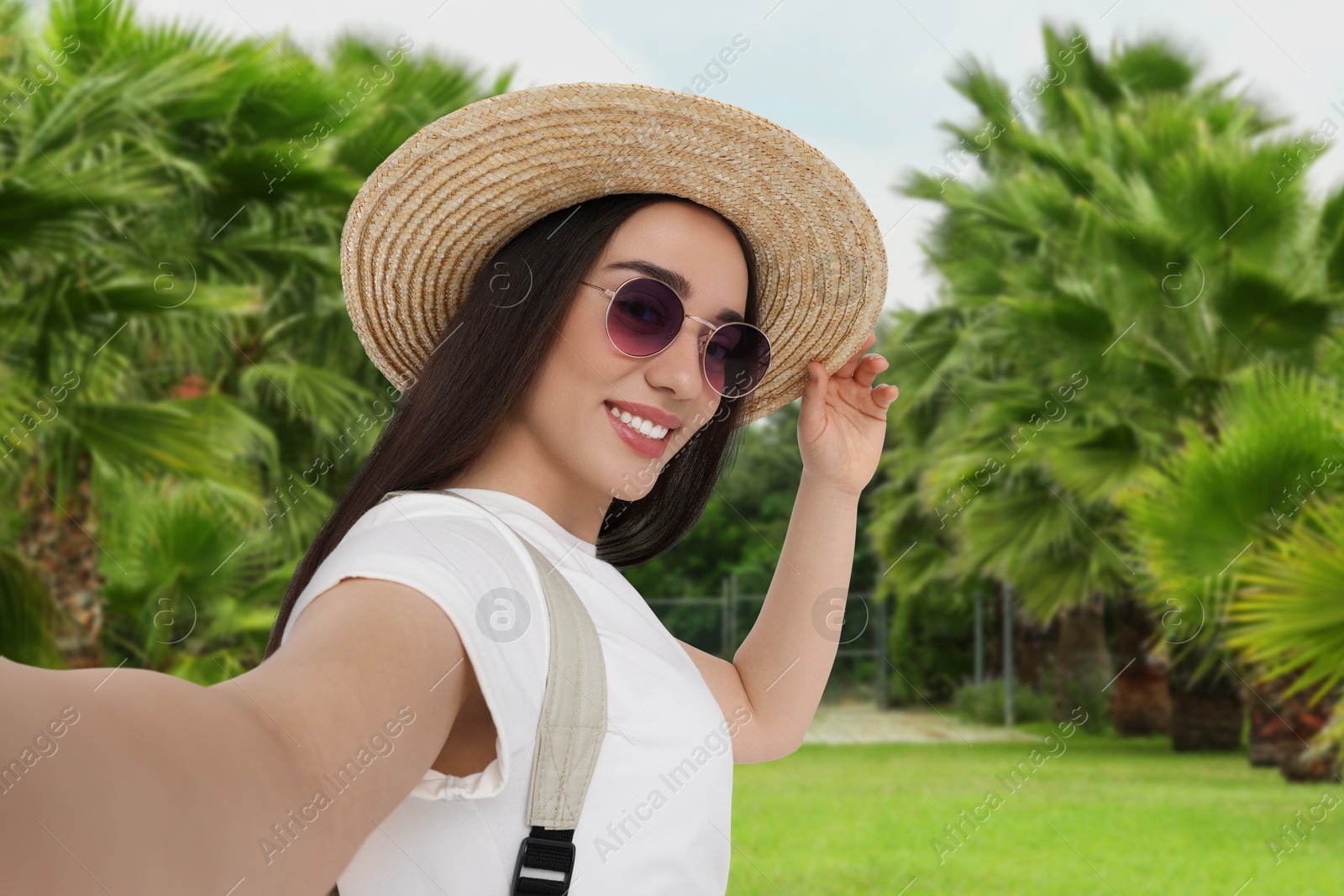 Image of Happy woman in straw hat taking selfie in nature