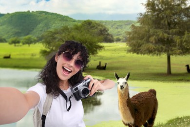 Beautiful woman with sunglasses and camera taking selfie in nature