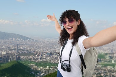 Image of Beautiful woman with sunglasses and camera taking selfie against city