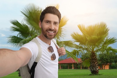 Happy man with sunglasses taking selfie near resort