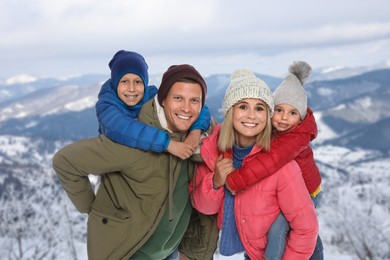 Portrait of happy family with children in mountains on winter day