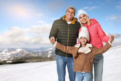 Image of Portrait of happy family with child in mountains on winter day