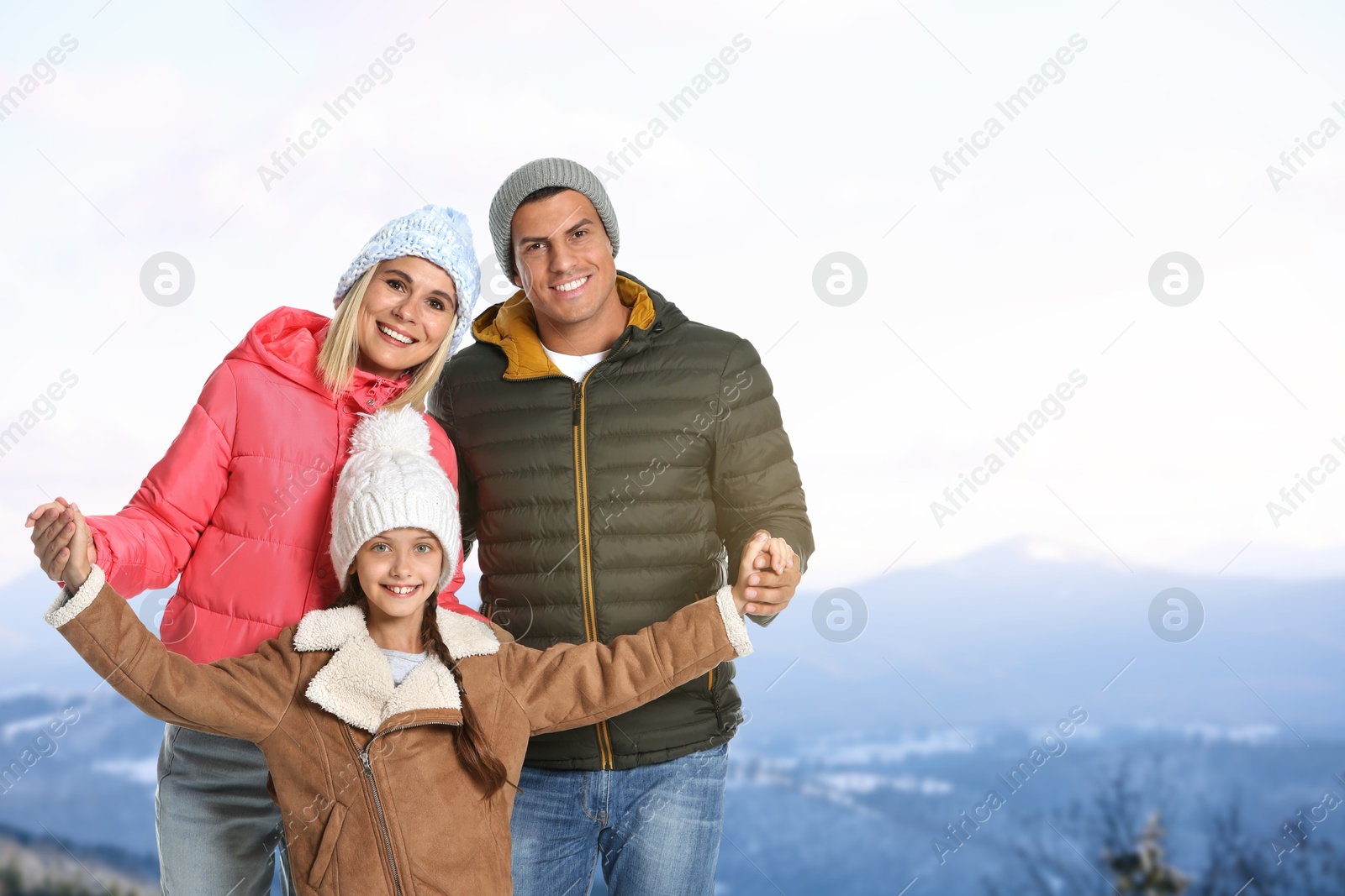 Image of Portrait of happy family with child in mountains on winter day