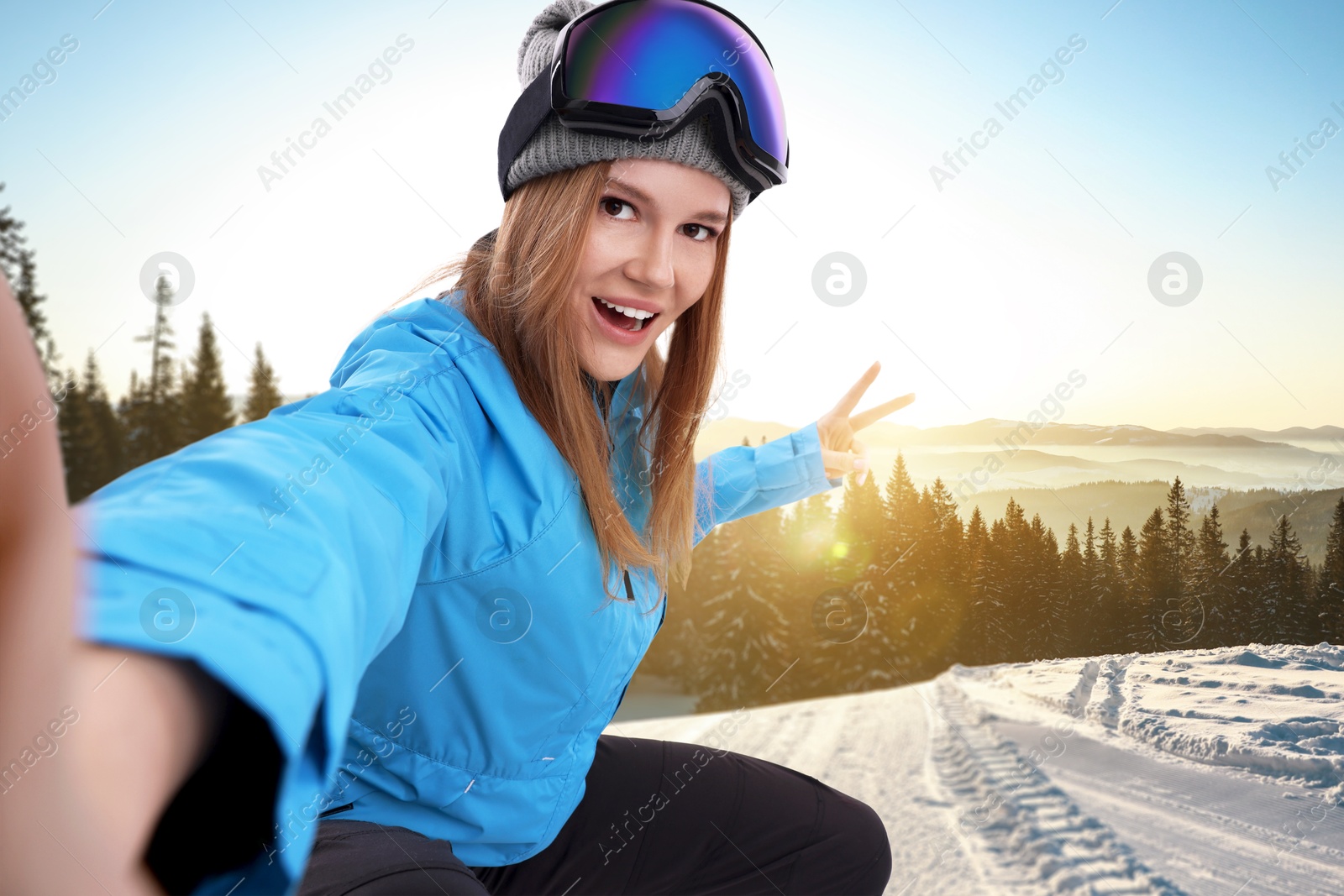 Image of Happy young woman with ski goggles taking selfie in mountains