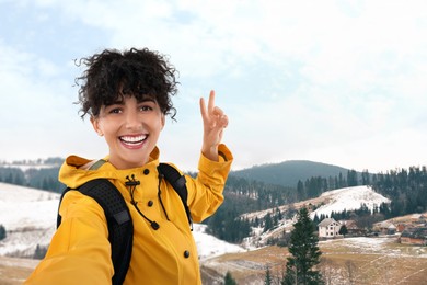 Image of Happy young woman taking selfie in mountains