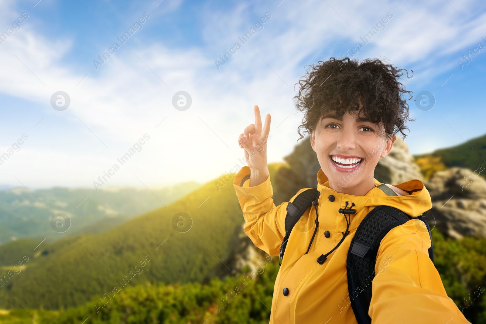 Image of Happy young woman taking selfie in mountains