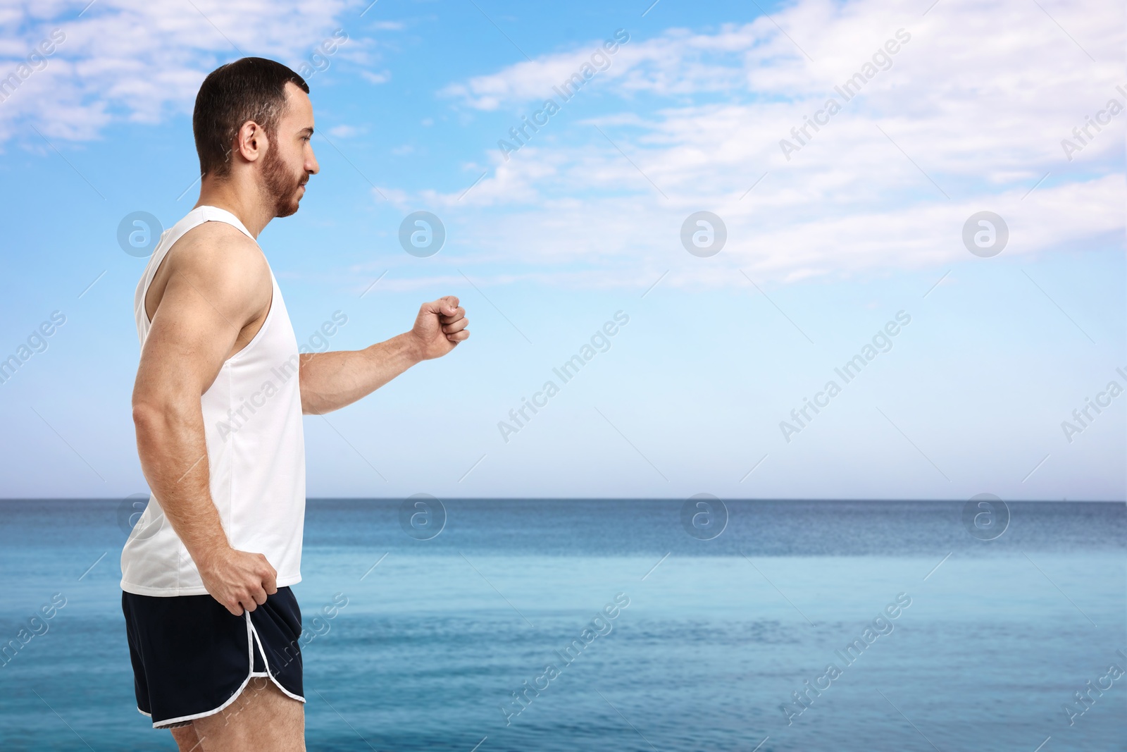 Image of Sporty man running on beach. Space for text