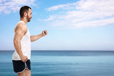 Image of Sporty man running on beach. Space for text